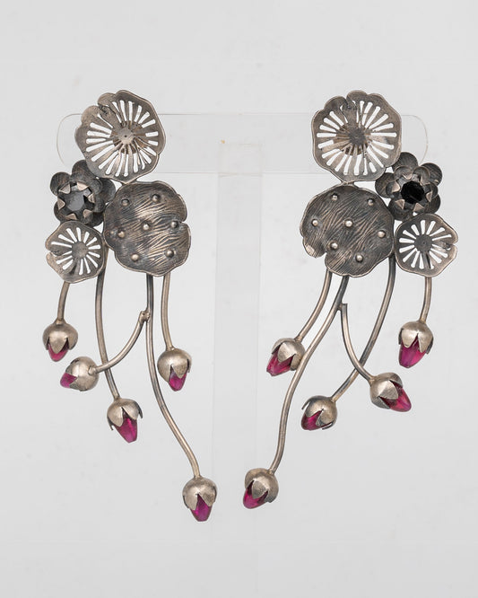 Pair of silver floral earrings with pink accents on a light gray background