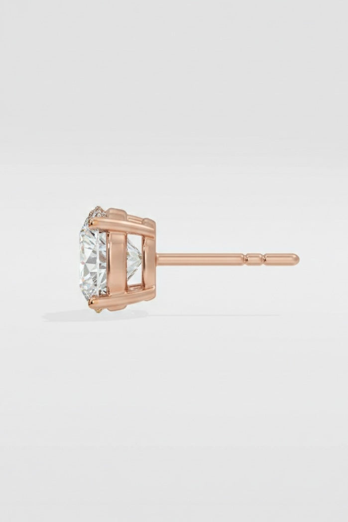 Rose gold stud earring with a clear gemstone on a light gray background