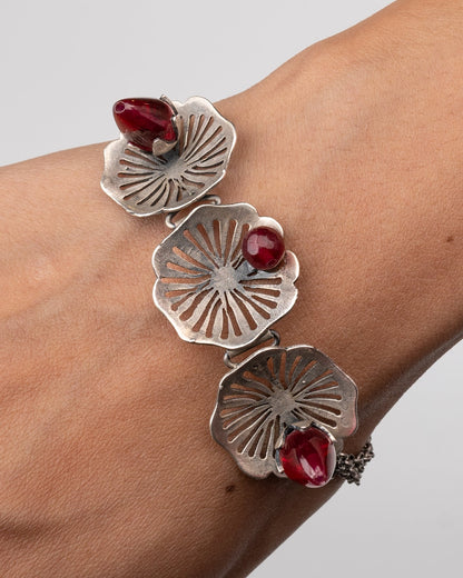Silver bracelet with Pink stones on a wrist against a gray background