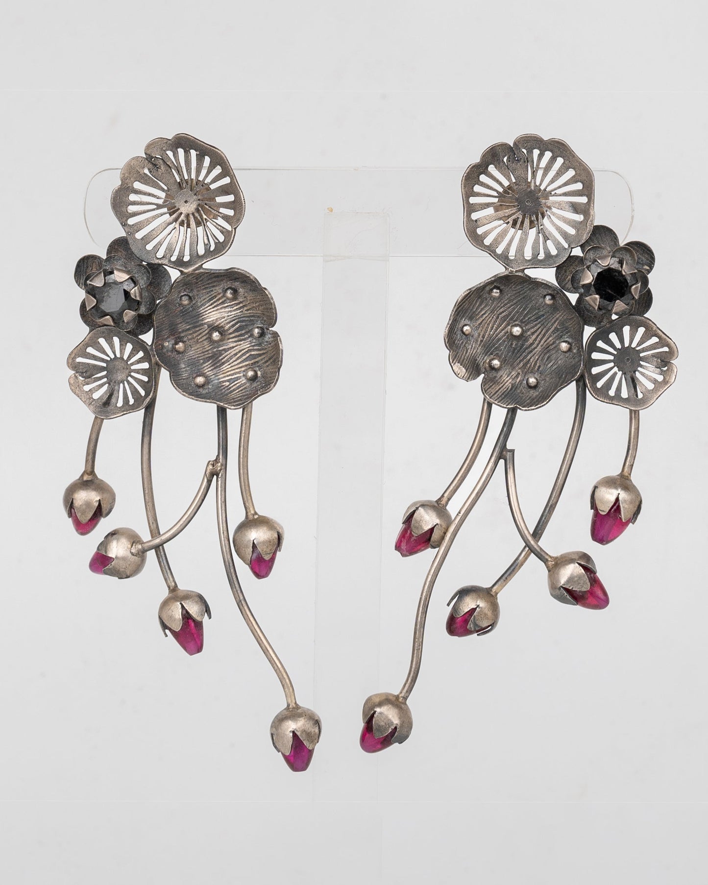 Pair of silver floral earrings with pink accents on a light gray background
