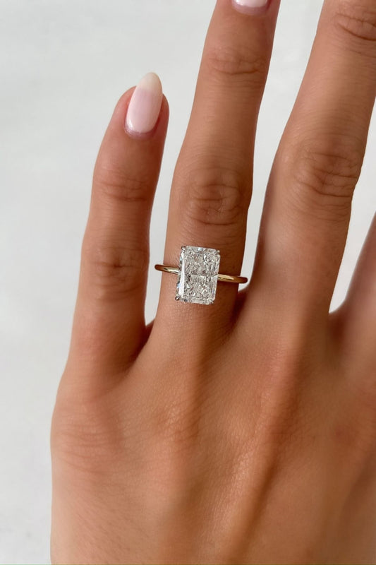 Radiant solitaire ring in gold worn on hand showing scale and sparkle
