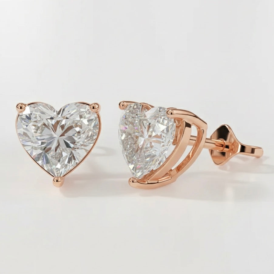 Heart-shaped diamond earrings with rose gold setting on a light gray background