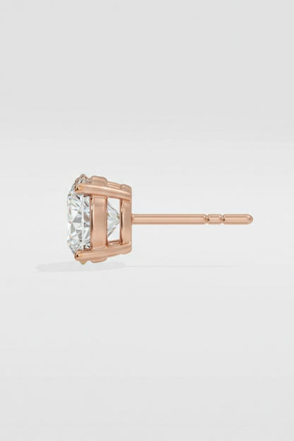 Rose gold stud earring with a clear gemstone on a light gray background