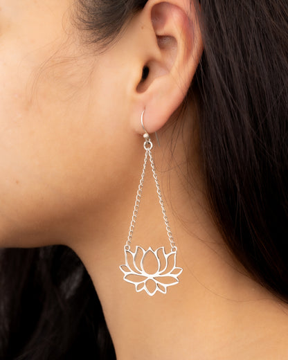 Silver lotus flower earring worn by a person
