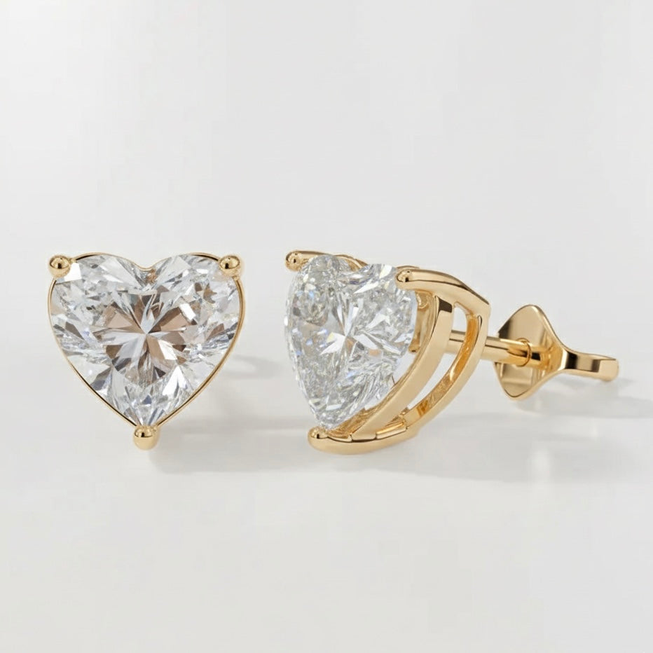Heart-shaped diamond earrings with gold settings on a light gray background