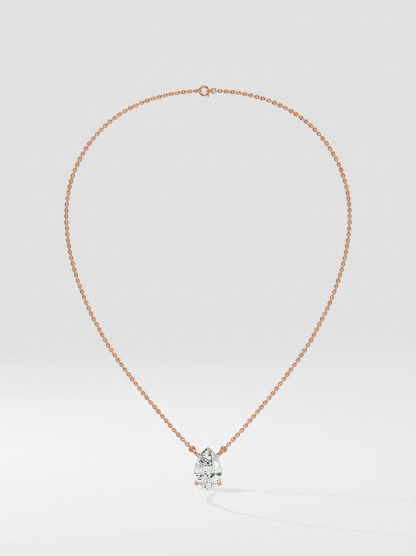 Rose gold necklace with a pear cut diamond pendant on a light gray background