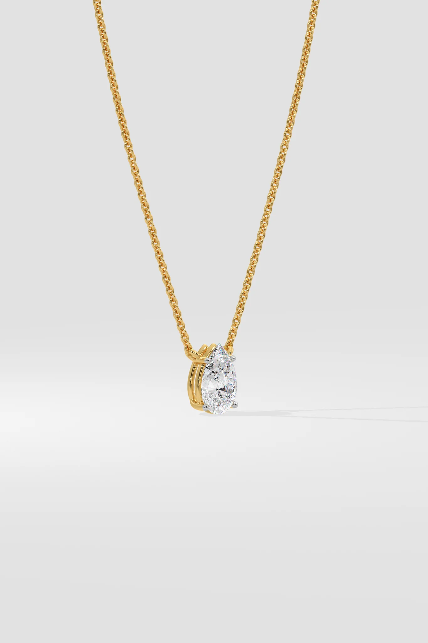 Side profile of custom pear cut diamond necklace in gold highlighting setting and chain