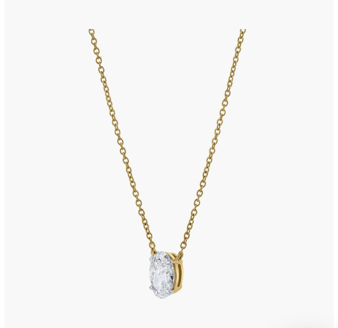 Side profile of custom oval solitaire diamond necklace in gold highlighting setting and chain